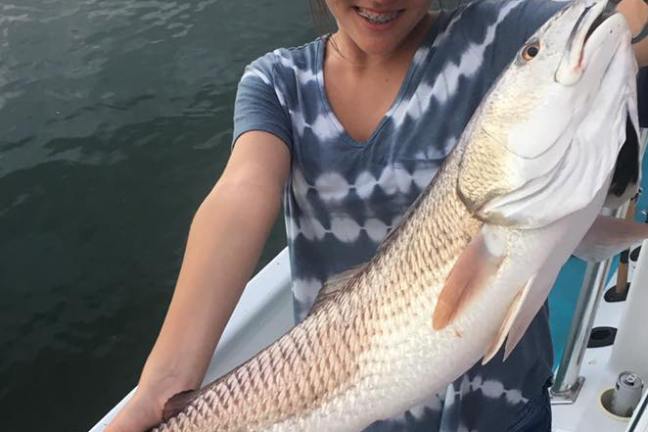 Young girl holding up big fish she caught on the boat