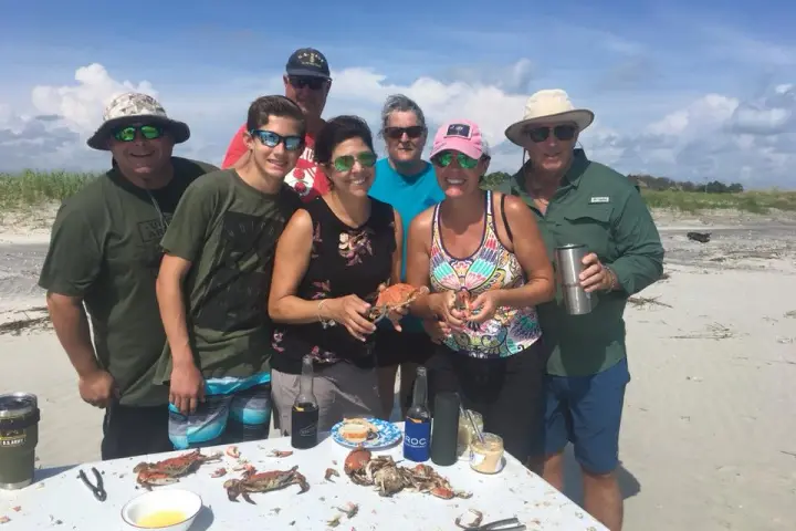 Group smiling together on the beach while shucking crabs