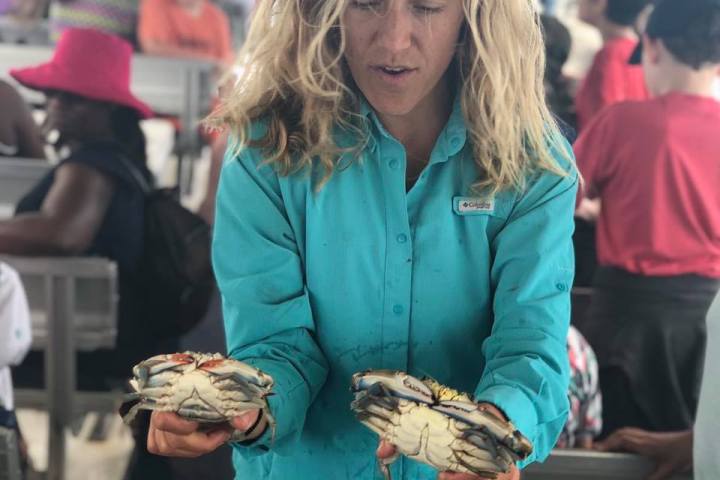 Woman holding two blue crabs