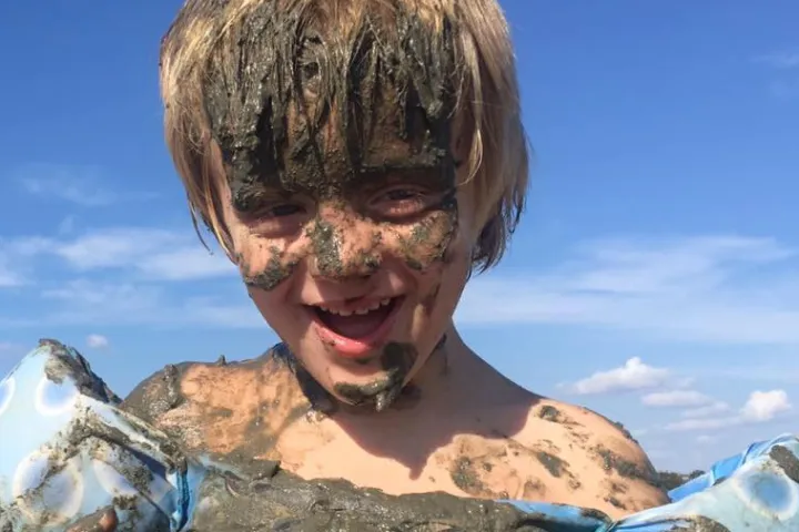 young boy covered in mud