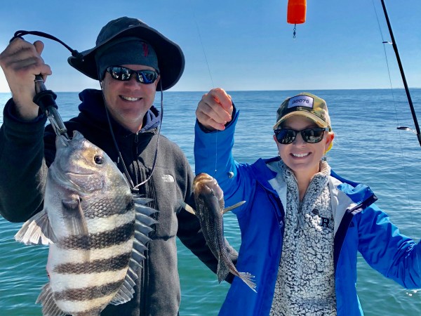 Man and woman holding up fish caught on boat