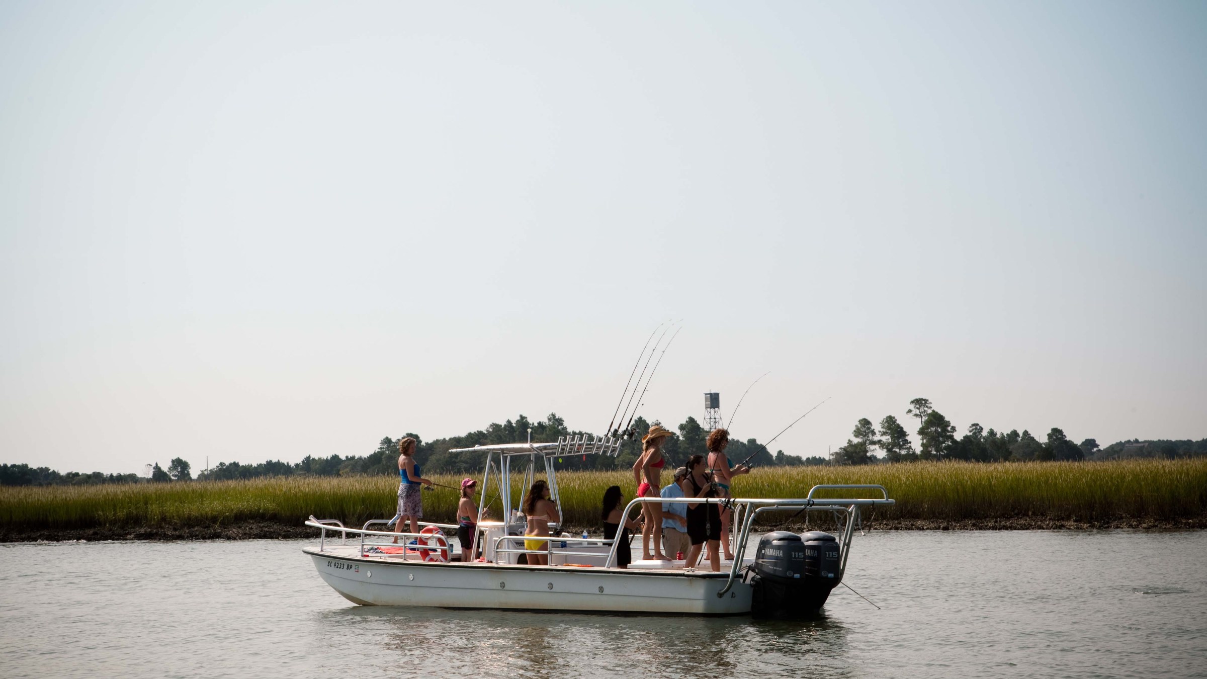 Group of women fishing off of skiff boat on river