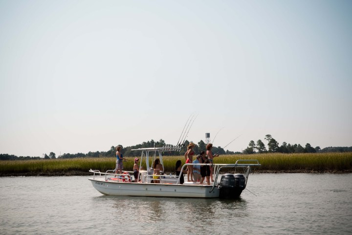 Group of women fishing off of skiff boat on river
