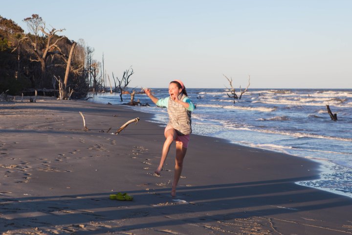 Girl jumping for joy while running on beach