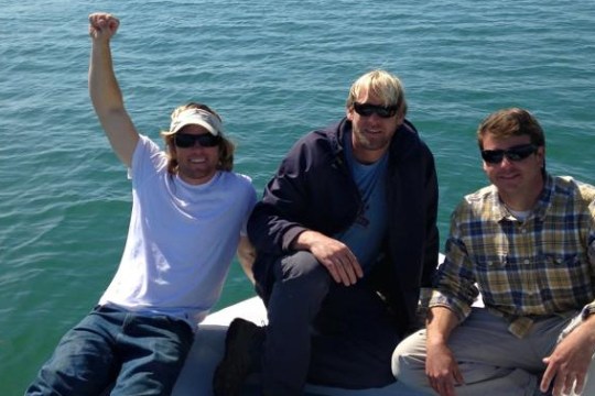 Three men sitting on bow of the boat