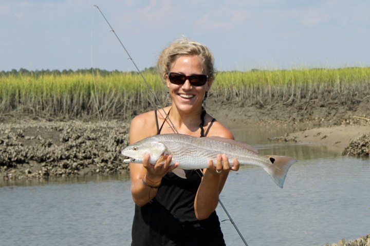 Woman holding up fish she just caught in river