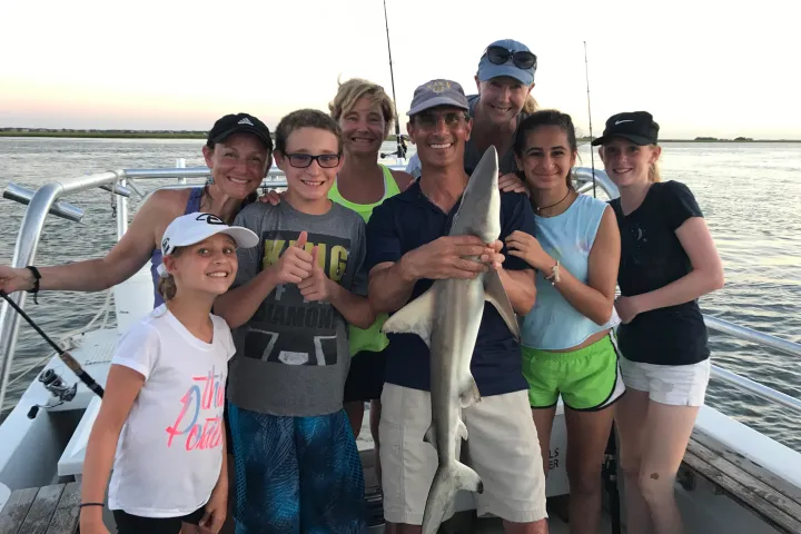 Family holding up small shark caught on fishing trip