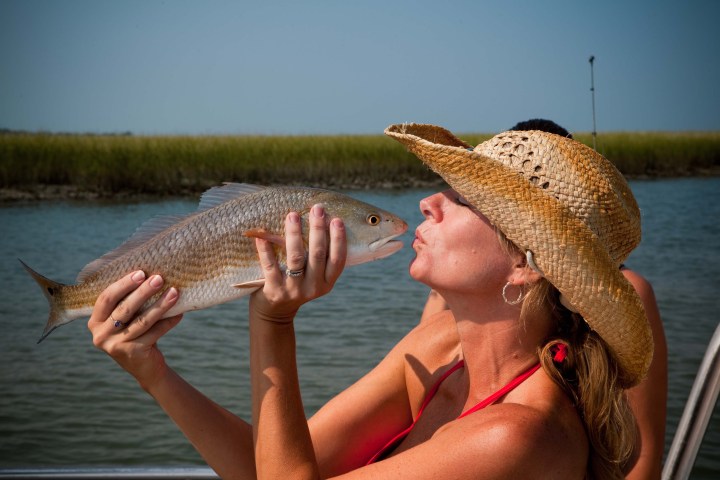 Lady acting like she is about to kiss a red fish