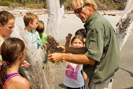 Tour guide showing small children plant life on an island