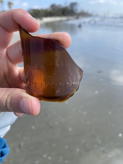 a hand holding a piece of broken glass on the beach