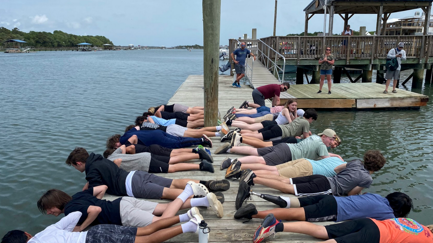 a group of people sitting on a dock next to a body of water