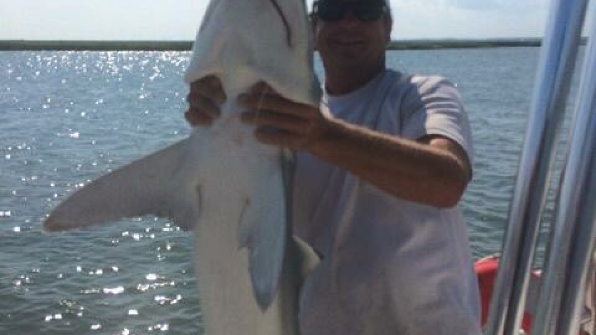 a person holding a fish in front of a body of water