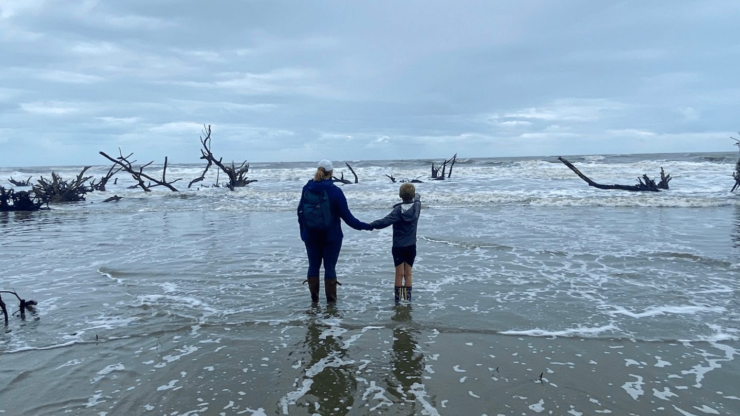 a group of people walking across a beach next to the ocean